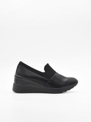 Zapato deportivo de mujer color negro, con diseño slip on sin cordones y suela con cuña interna de plataforma ligera.