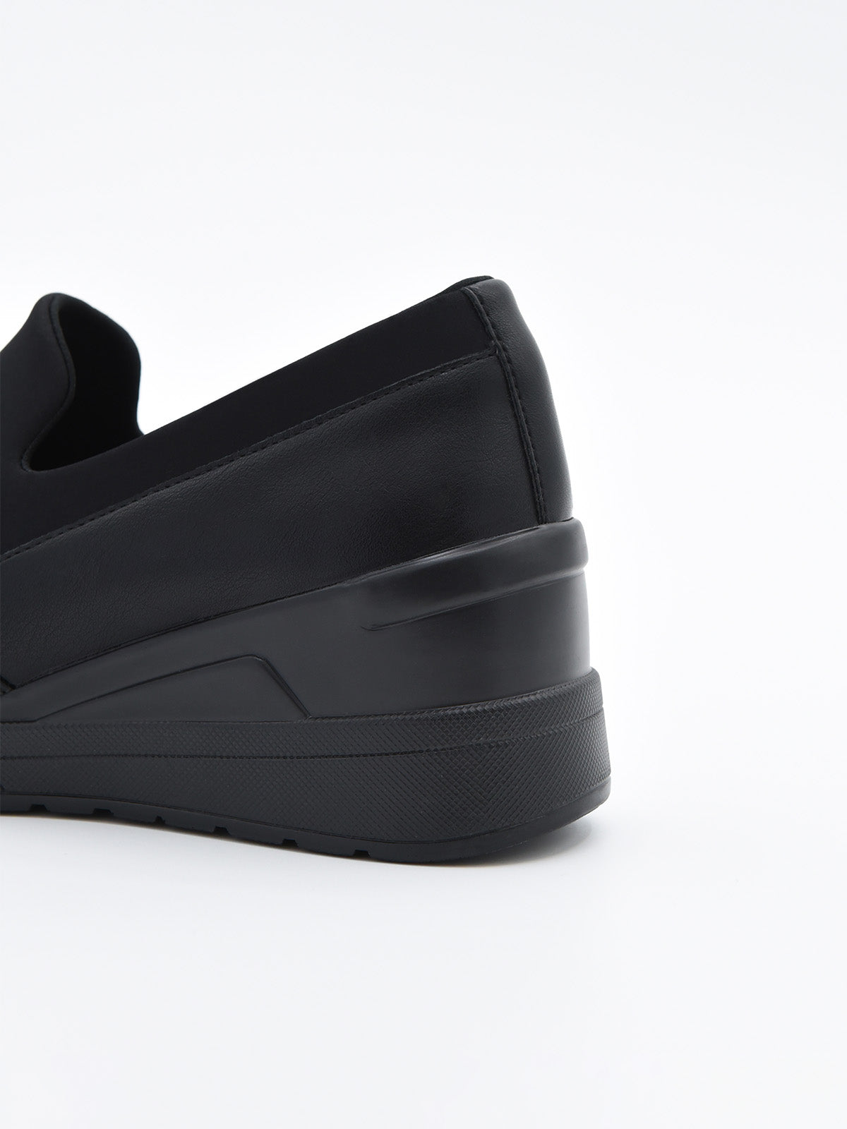 Zapato deportivo de mujer color negro, con diseño slip on sin cordones y suela con cuña interna de plataforma ligera.