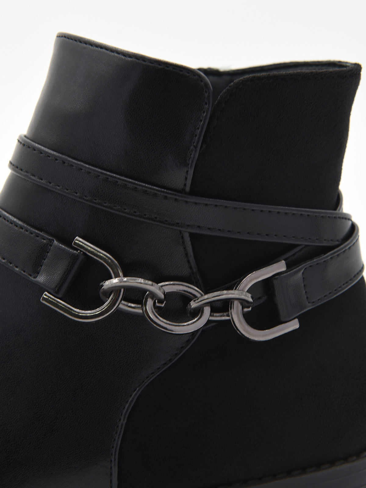 Botín negro de mujer en material sintético efecto piel, con detalle de cadena metálica lateral y tacón bajo ancho.