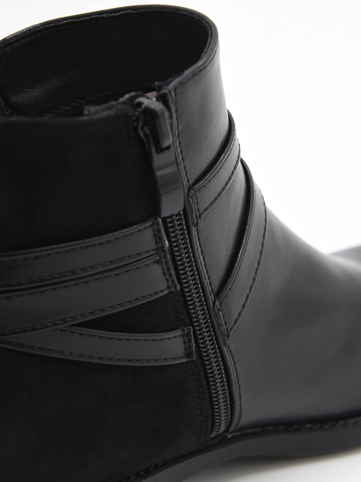 Botín negro de mujer en material sintético efecto piel, con detalle de cadena metálica lateral y tacón bajo ancho.