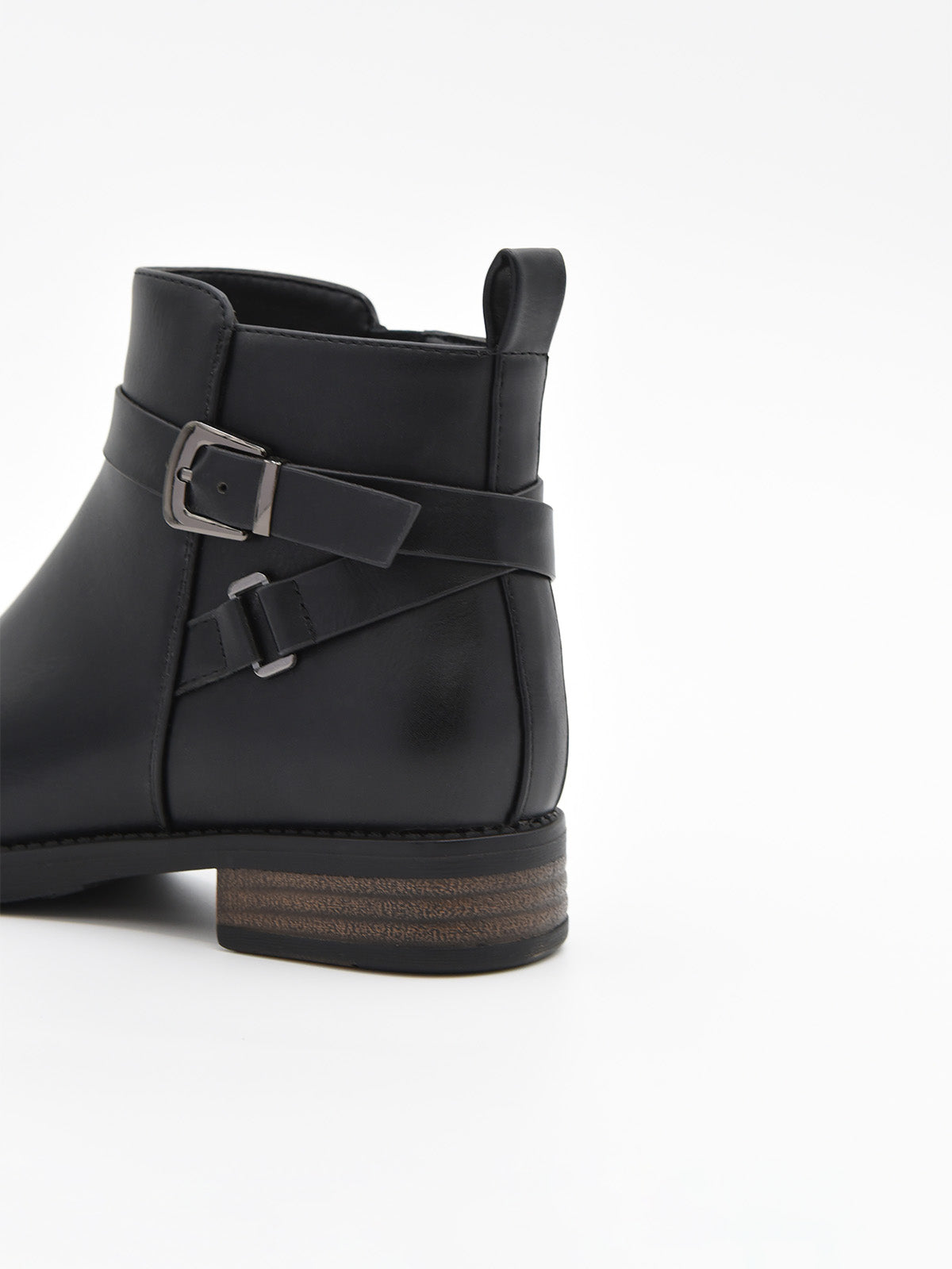 Botín de mujer en material sintético negro efecto piel, con hebilla lateral metálica y tacón bajo ancho con detalle de madera.