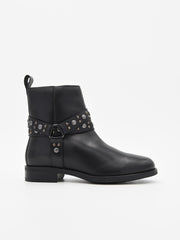 Botín de piel negro con correas decoradas con tachuelas metálicas y cremallera lateral. Tacón bajo, estilo rock chic elegante.