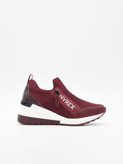 Zapatillas slip-on burdeos de tejido transpirable con cuña interna blanca, suela bicolor y refuerzo brillante en el talón.